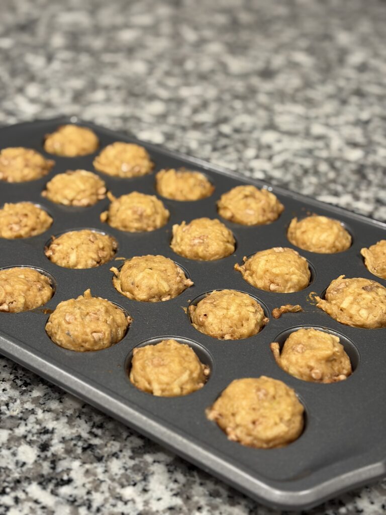 Mini muffin pan filled with apple cinnamon muffin batter before baking