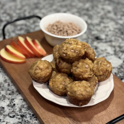 Apple cinnamon chip mini muffins on a plate with apple slices and a bowl of cinnamon chips
