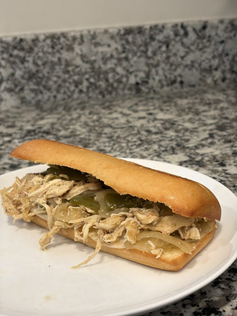 Chicken Philly cheesesteak on a toasted hoagie roll with melted provolone, peppers and onions